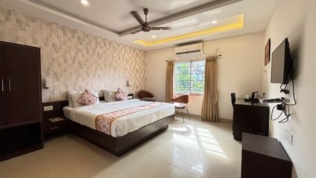 Spacious hotel room with a double bed, natural light, a seating area near the window, and modern amenities at Sumitel Premier Inn.