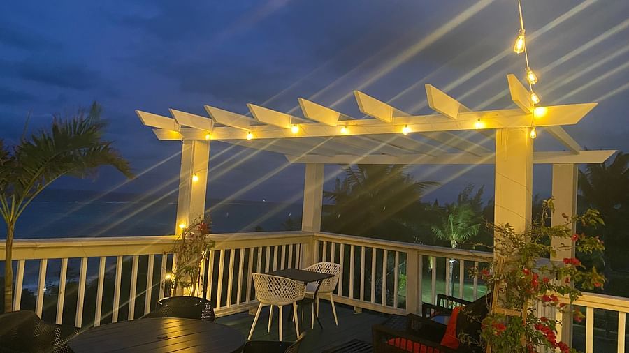 Outdoor seating area under pergola with string lights at night | A Stone's Throw Away