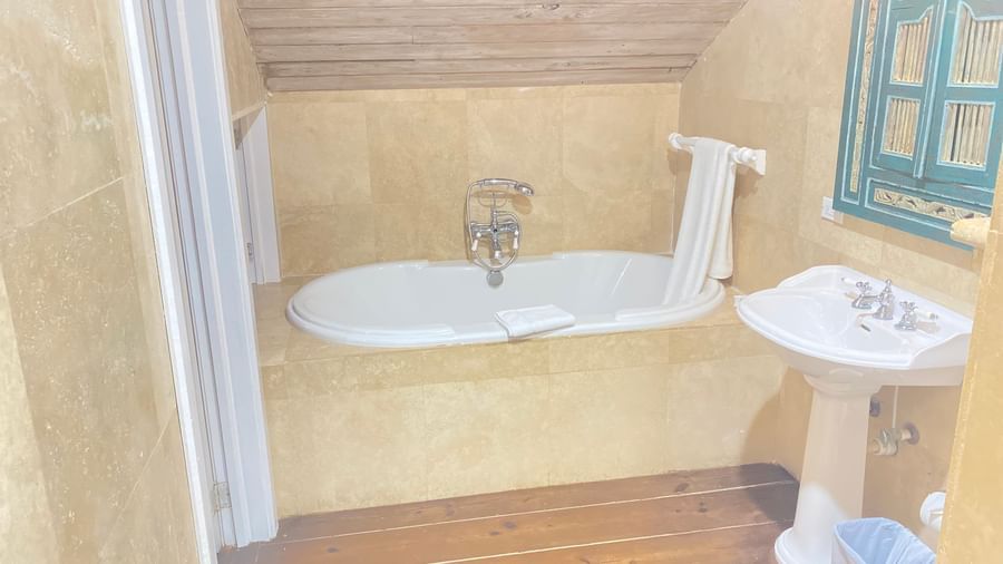 A bathroom with a freestanding bathtub under a sloped ceiling | A Stone's Throw Away