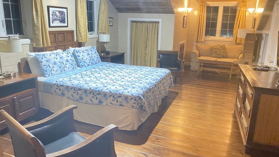 A warmly lit bedroom with a bed, wooden floor, wooden furniture, and beige walls | A Stone's Throw Away