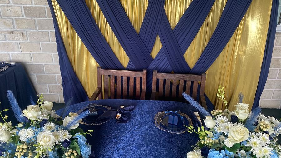 A table setup decorated with floral arrangements and a navy blue and gold backdrop | A Stone's Throw Away
