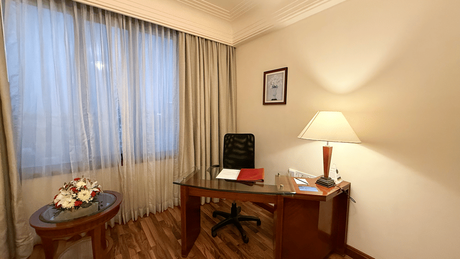 The Superior Room with a work desk, chair, and floor lamp beside a large curtained window at Accord Metropolitan.