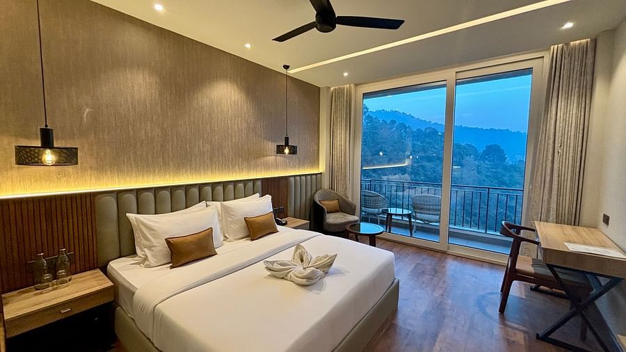 Cosy double bedroom with wooden flooring, ceiling fan, and balcony offering scenic views – ARNISA Boutique Hotel