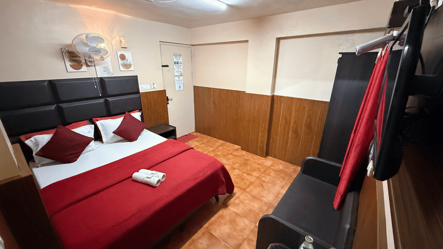 Deluxe Double Room with Extra Cot at BN Tourist Home, Ooty featuring a double size bed, fan, sofa, bedside table, and a flat tv screen.