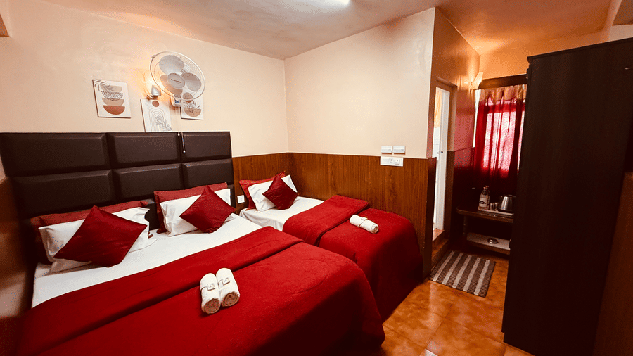 Deluxe Triple Room at BN Tourist Home , Ooty featuring a double size bed, a single bed, a fan, a tea and coffee maker, and wardrobe.