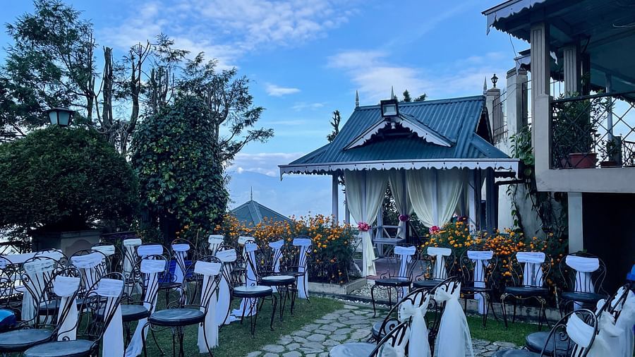 Outdoor seating setup at Cedar Inn, Darjeeling, arranged on the lawn with scenic views and a stage area for events or celebrations.