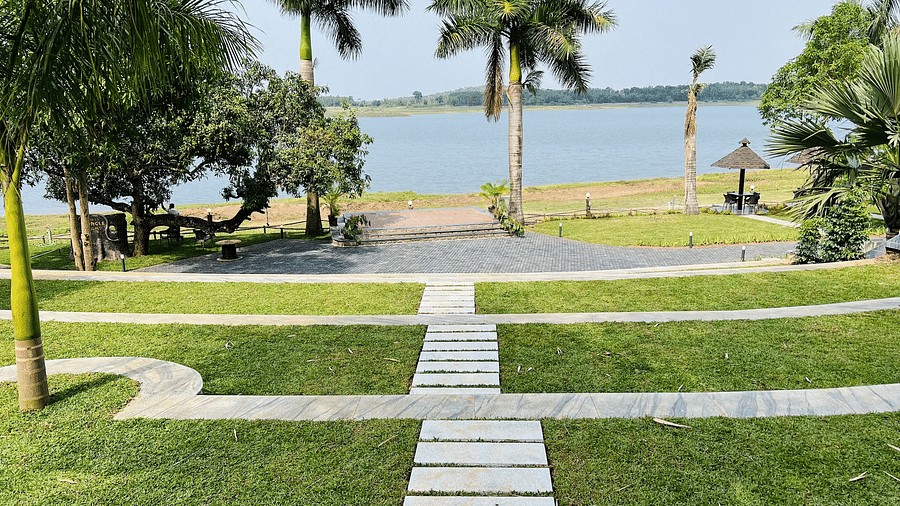 Stone pathway on patches of grass leading to a viewpoint facing the backwaters at Coorg Jungle Camp Backwater Resort in Kushalnagar.