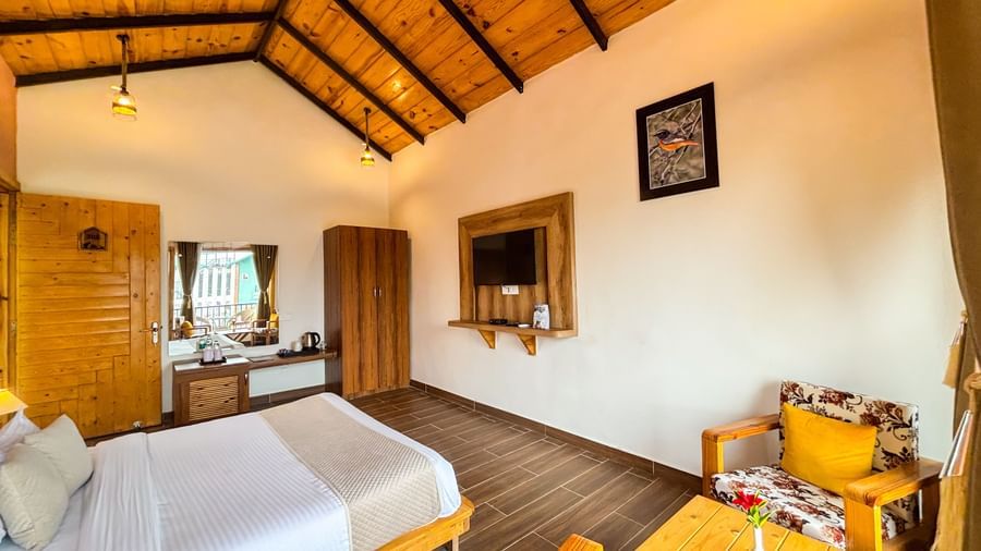 Resort room with sloping wooden ceiling, twin beds, and rustic yet stylish decor at Corbett Nirvana Resort.