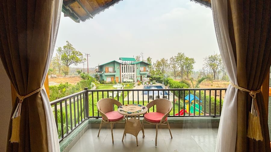 Balcony with seating area overlooking greenery at Corbett Nirvana Resort.
