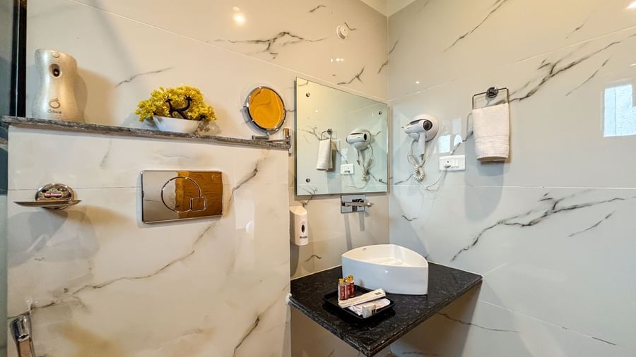 Contemporary bathroom with marble walls, vanity counter, and elegant amenities at Corbett Nirvana Resort.