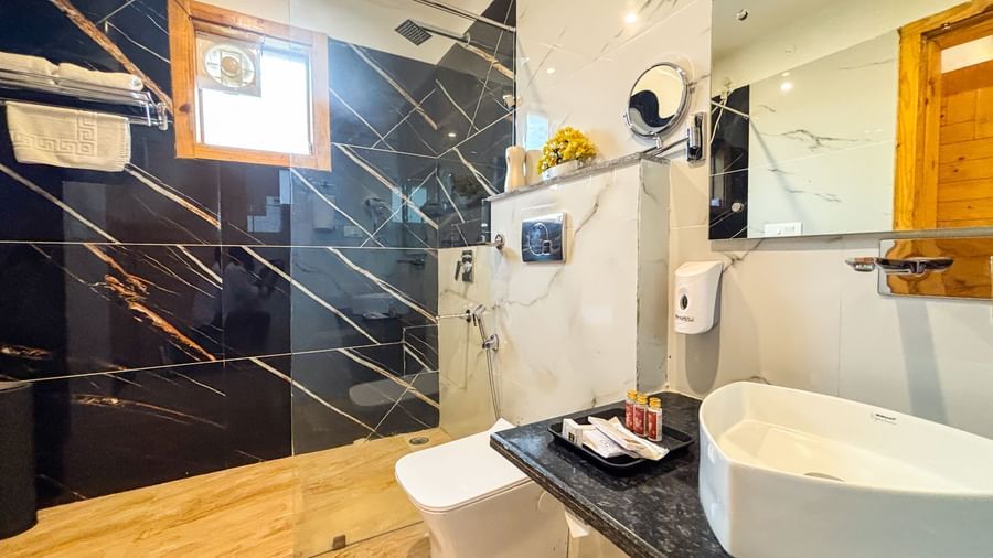 A sleek, modern bathroom featuring dark marble tiles, a white basin sink, and clean lines at Corbett Nirvana Resort.