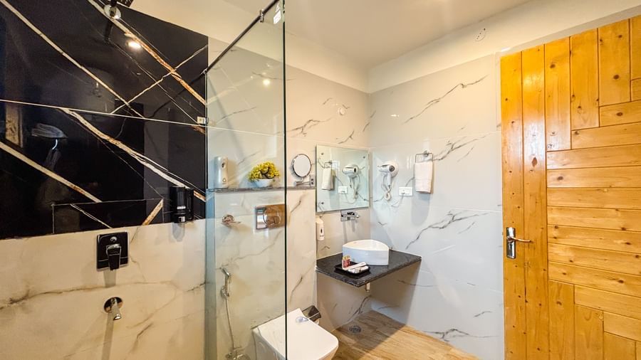 Modern bathroom with glass shower enclosure and premium fittings at Corbett Nirvana Resort.