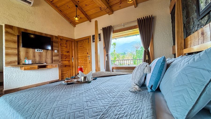 Comfortable resort room with king size bed, TV unit, and warm interiors at Corbett Nirvana Resort