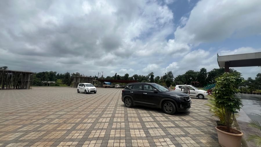 Outdoor parking area of Daksh The Valley Resort, Saputara, seen on a cloudy day, with few cars standing in the tiled ground.