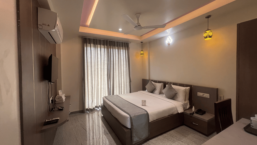 Wide view of the Superior Room with Mountain View at Daksh The Valley Resort, Saputara, featuring its queen size bed, closed curtains, and designer ceiling.