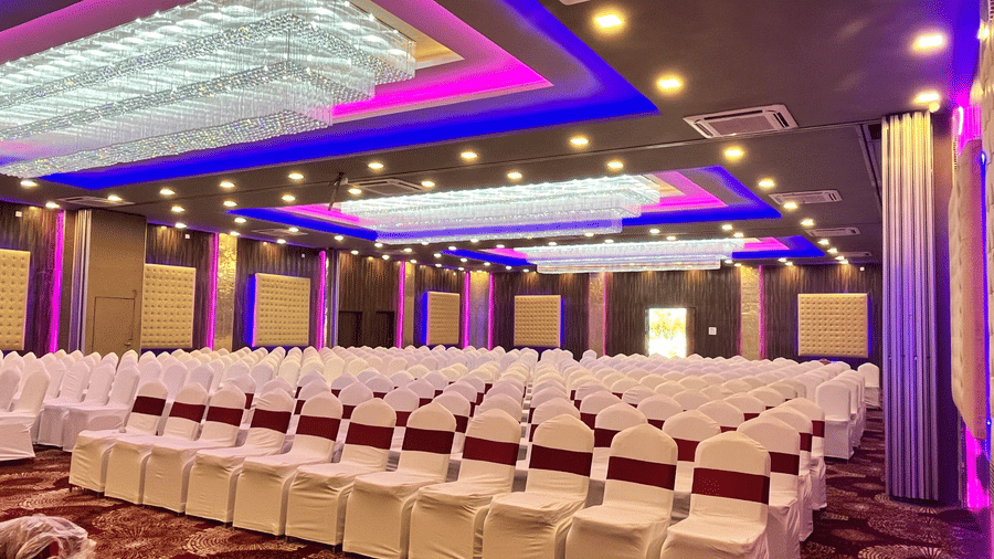Large conference and wedding venue arranged with rows of seating and modern ceiling fixtures - DAN Resorts & Weddings, Palghar
