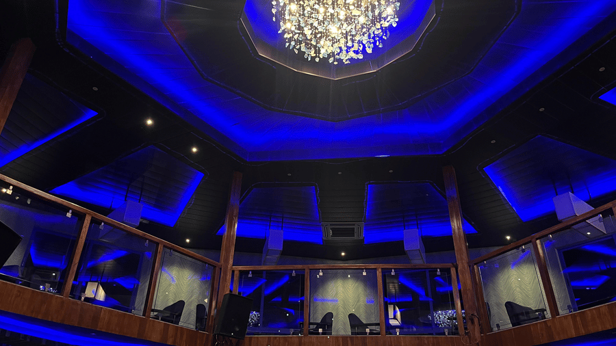 Looking up at a large crystal chandelier and vibrant blue neon ceiling lights in the ballroom - DAN Resorts & Weddings, Palghar