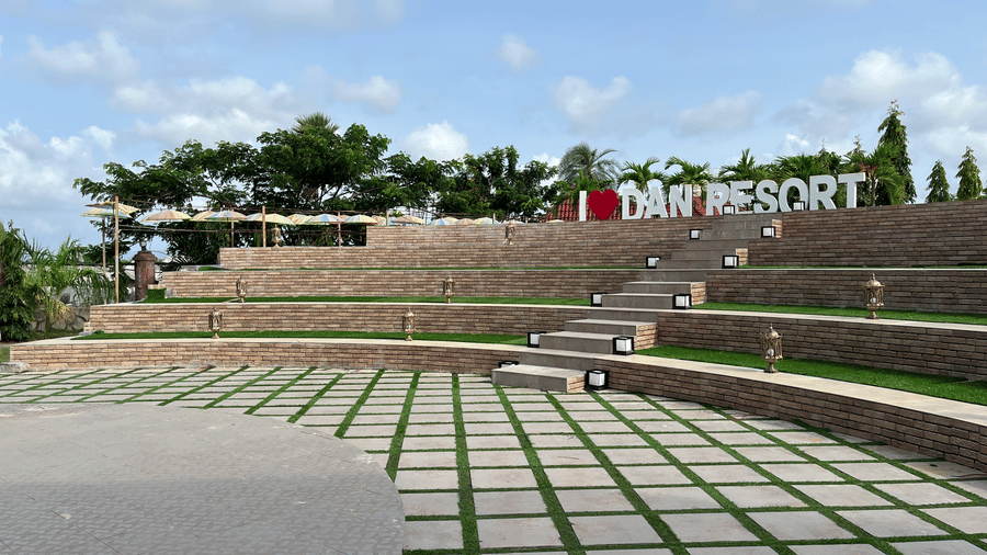Wide view of the resort's outdoor amphitheatre featuring green grass accents between stone steps - DAN Resorts & Weddings, Palghar