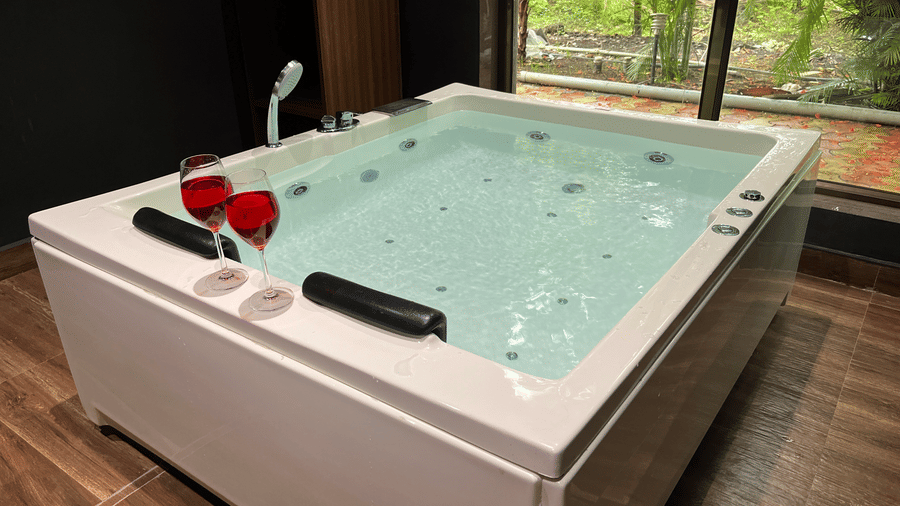 Luxury indoor jacuzzi tub set up with wine glasses for an intimate experience - DAN Resorts & Weddings, Palghar