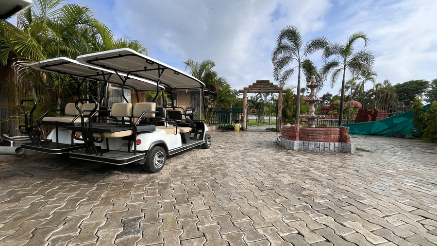 Electric golf carts parked in a paved courtyard area, ready for guest transport - DAN Resorts & Weddings, Palghar