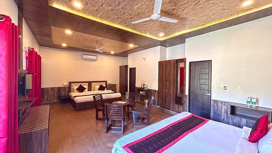 A Family Cottage with beds facing towards each other seperated by a round dining table and TV at DLS MJ River Resort, Rishikesh.