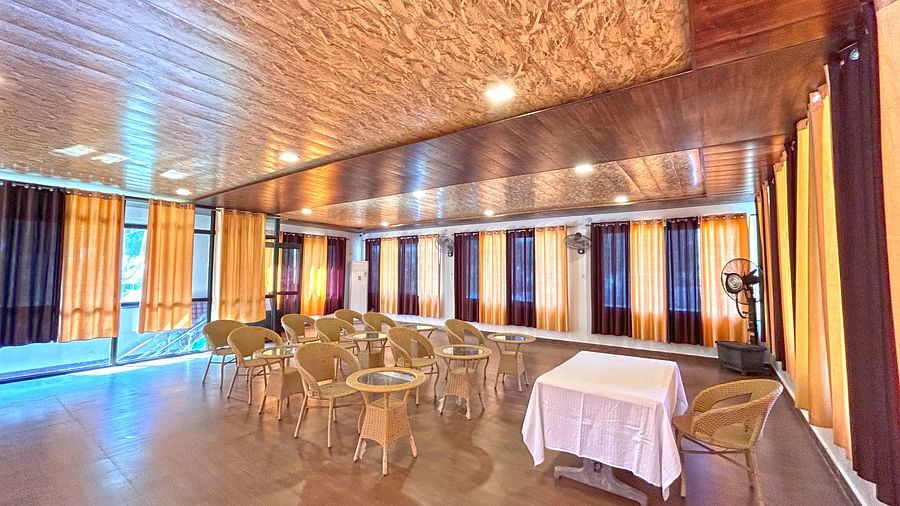 A conference hall with ambient lighting and chairs facing a white table at DLS MJ River Resort, Rishikesh.