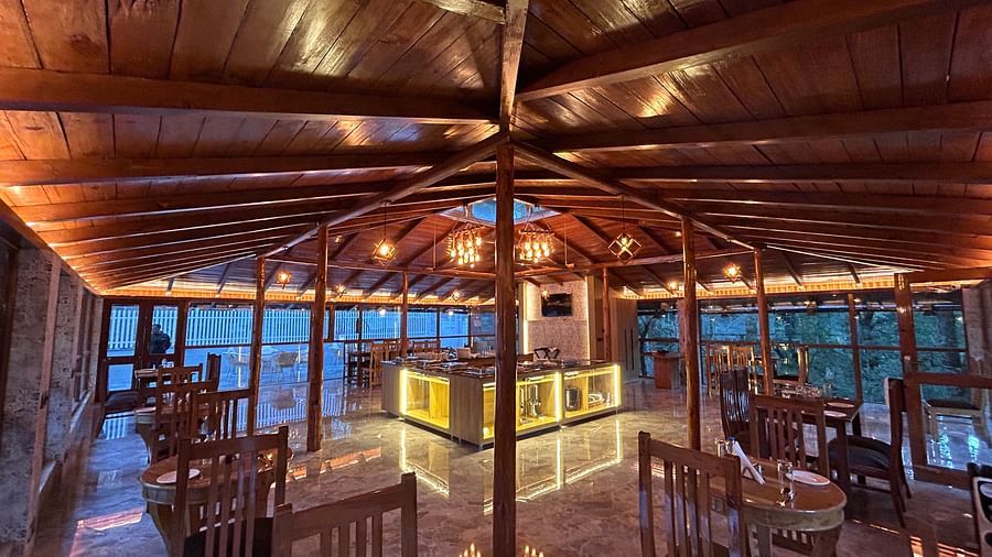 An image of the restaurant at DLS The Emerald, Nainital with wooden interiors along with chairs and tables and the area is lit with bright lighting