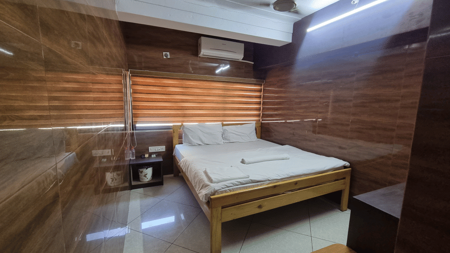 Standard Double Bed A/C Room featuring a double bed with a wooden frame, an A/C unit, and a ceiling fan, at Dream Vision Guest House, Diu.