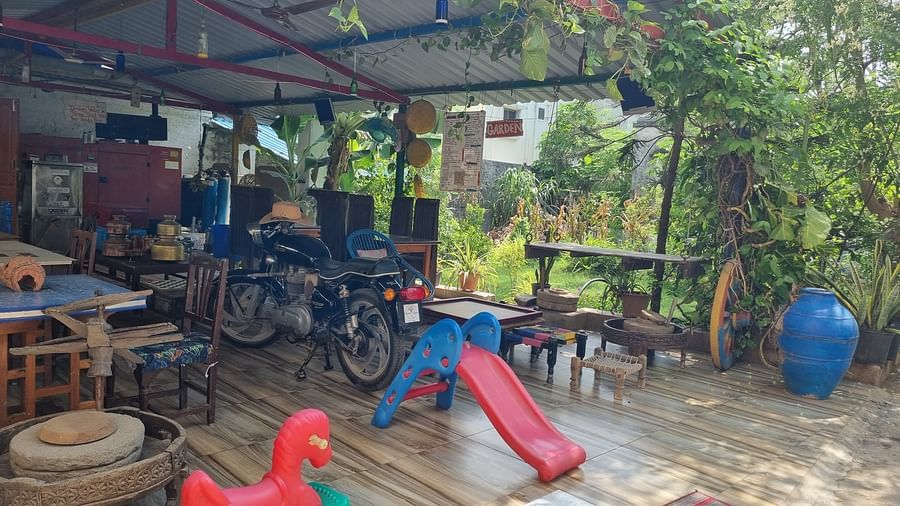 The kids' play area with surrounded by lush greenery along with a motor cycle kept under the shed at Dream Vision Guest House.