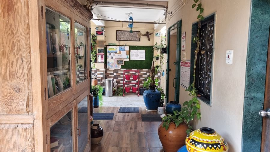 The corridor at the Dream Vision Guest House in Diu featuring a huge wooden cabinet along with several potted plants.