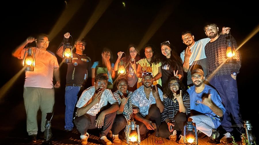 Several young adults posing with lanterns at night, expressing happiness and unity in a natural setting - Evergreen County