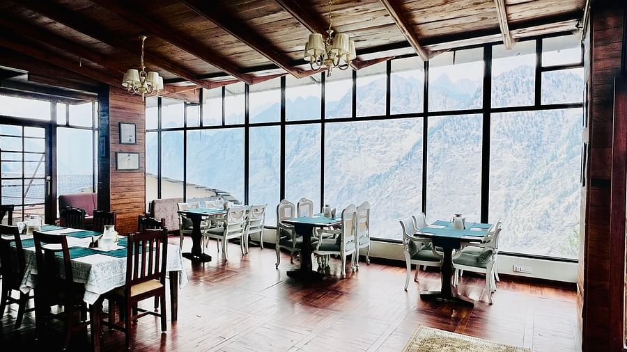 Wood-paneled dining room with large windows offering panoramic views of the mountains  | Faraway Cottages, Auli