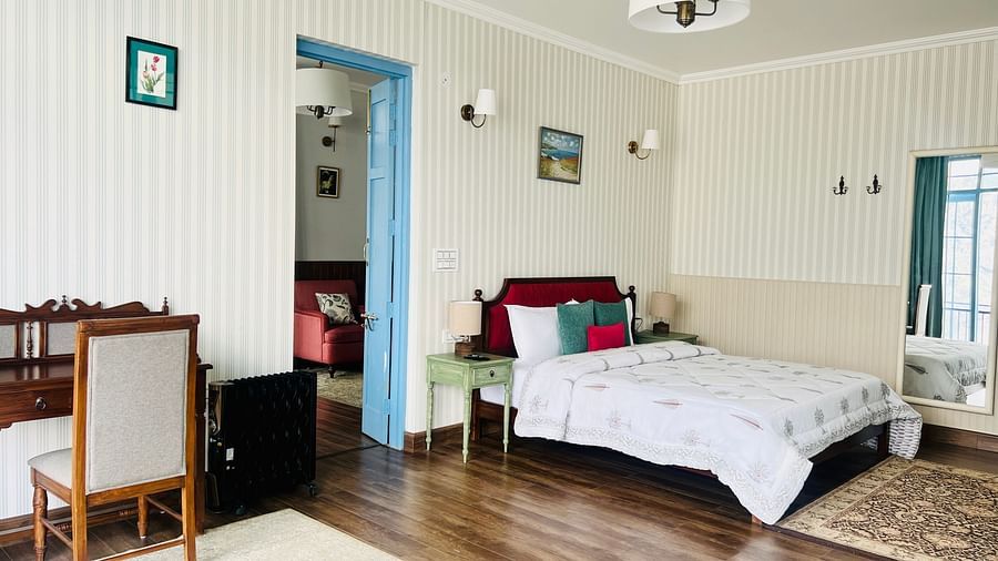 An image of a suite with bed, a table and chair, and bathroom attached | Faraway Cottages, Auli