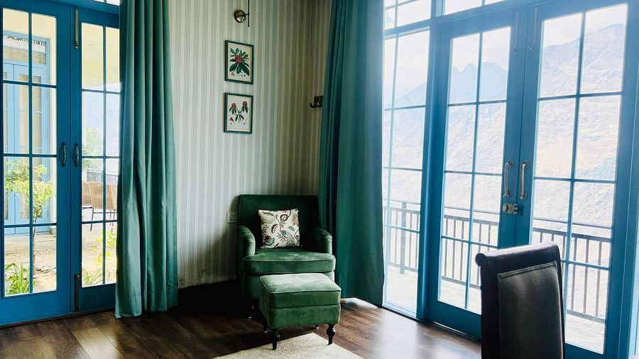 A sitting area with two chairs at each corners and large windows beside them  | Faraway Cottages, Auli