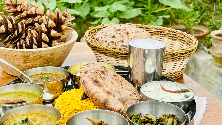 Traditional meal with various dishes, bread, and pine cones served outdoors on a table surrounded by greenery at Faraway Cottages