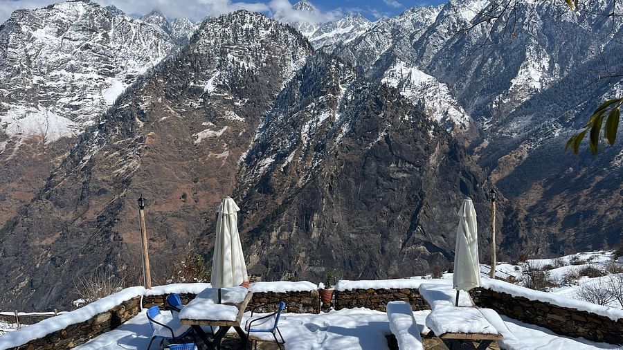 Image of outdoor seating area filled with snow and mountains in the background | Faraway Cottages, Auli