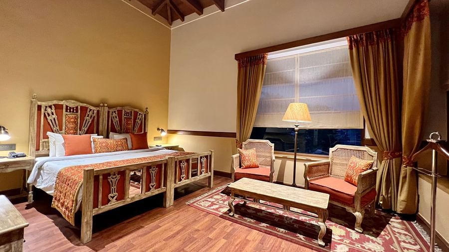 A cozy Superior Lake Facing Room at Fishermen's Lodge, Bhimtal, featuring a comfy bed, sofa, and table, perfect for relaxation.