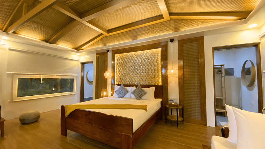 Spacious beachfront villa bedroom with vaulted ceiling, signature textured headboard, and warm lighting at Flower Island Resort Imperial Villa.