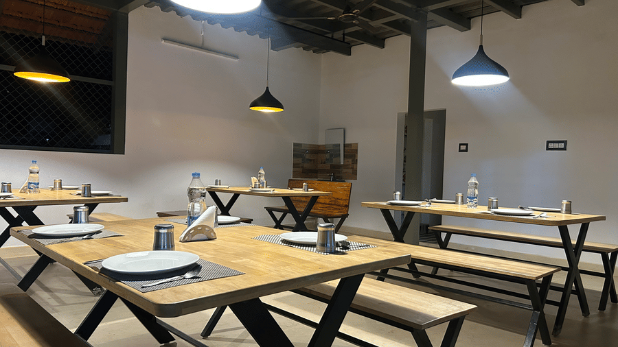 An illumintaed dining area at Hatti Eden Coorg, with tables and chairs set for dining.