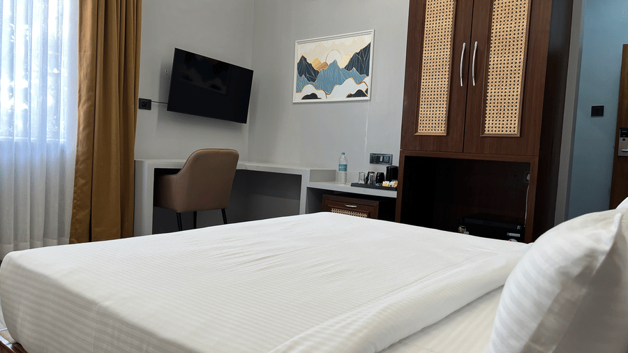 Corner view of the Suite at Hotel Mumbai House, Pithampur, featuring a neat double bed with a wall-mounted television.