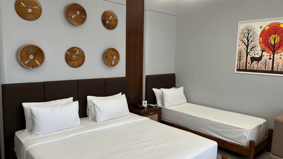 A double bed and a single bed at the Suite with several circular wall art hung on the wall above the headboard of the bed at Hotel Mumbai House, Pithampur.