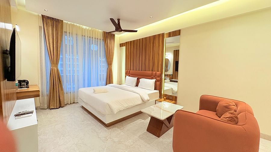 A spacious bedroom featuring a king size bed, a large sofa, and a wall-mounted television at Hotel Mumbai House, Vashi
