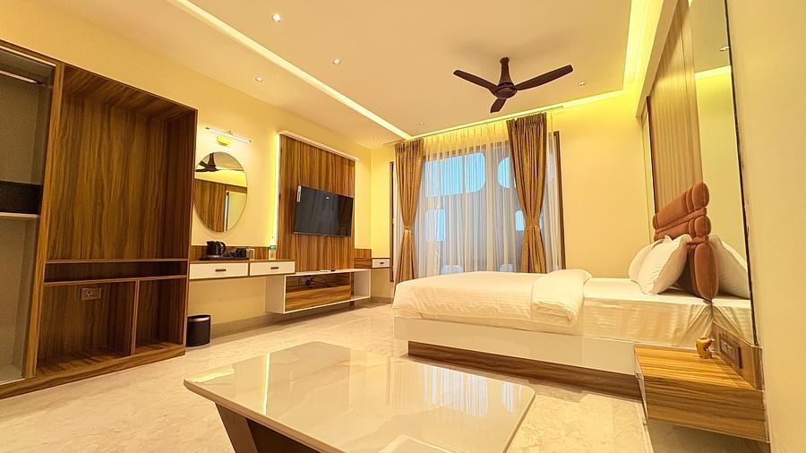 Side view of the bedroom featuring a wall-mounted television, a king size bed, and a window covered by curtains at Hotel Mumbai House, Vashi.
