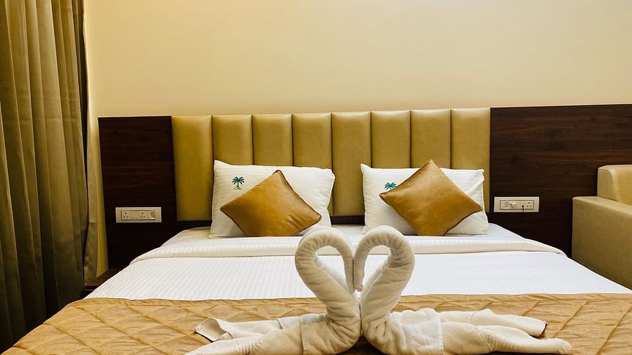 Romantic towel swan decor placed on a neatly arranged bed with golden accents at Hotel Sahara Tree.