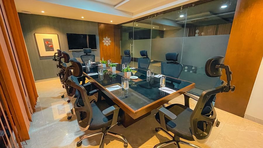 a room with a rectangular table surrounded by chairs and a mounted television - Jardin Hotels