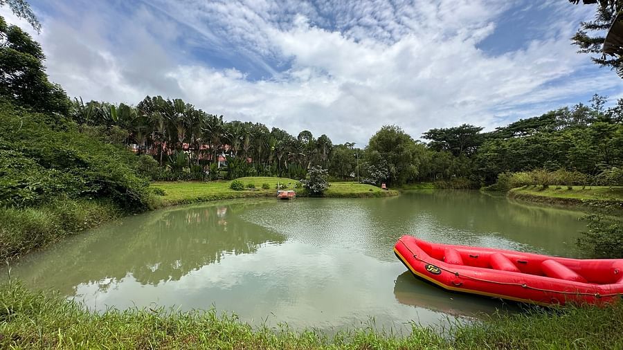image of a lake with a boat floating in it and trees visible in the distance - Kadkani River Resort, Coorg