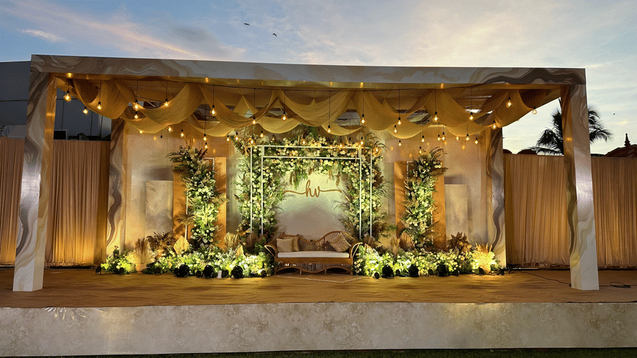 A grand outdoor wedding mandap beautifully decorated with gold pillars and lush floral arrangements under a clear sky - Kailash Conventions ECR