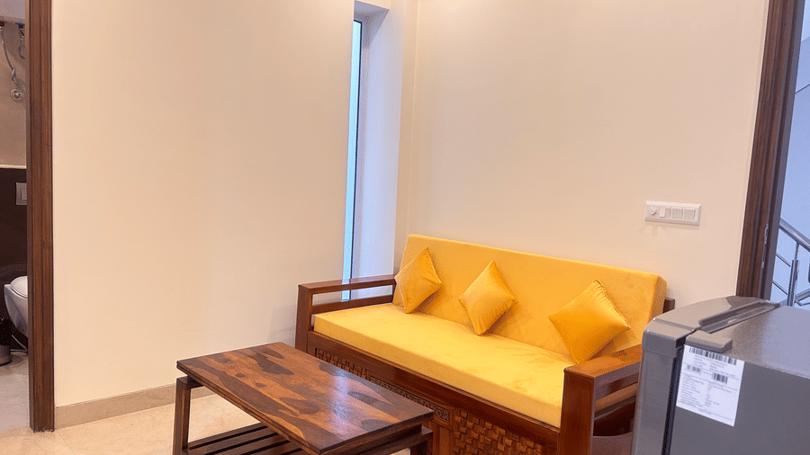 Living room of Lime Tree Hotels & Service Apartment Private Limited featuring a yellow sofa and a wooden coffee table.