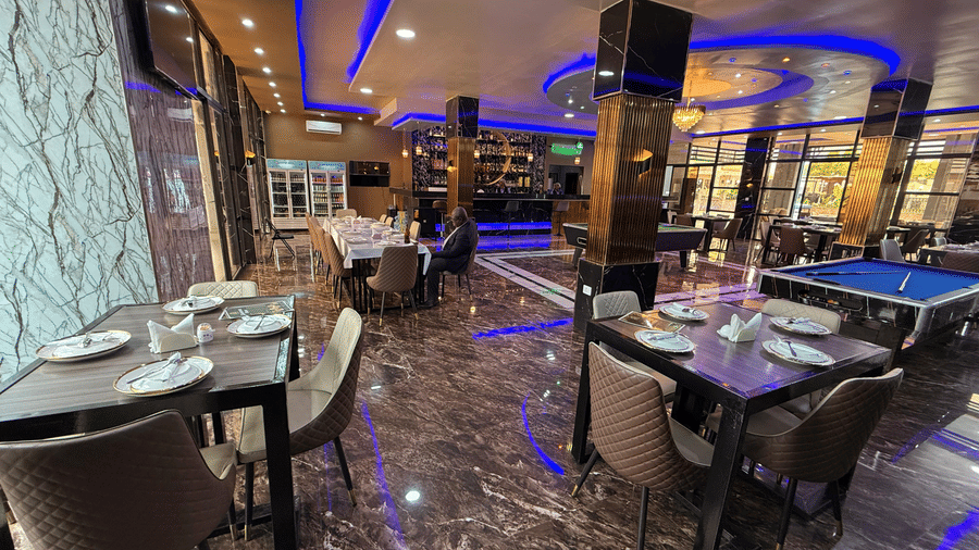 A lavish indoor dining area with marble-effect flooring, dark tables, place settings, and striking blue neon lighting at Luffu Club.