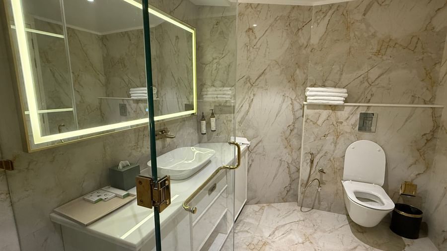 Luxurious bathroom with marble walls, glass shower enclosure, and illuminated mirror - Mayfair Cafe & Suites, Dalhousie